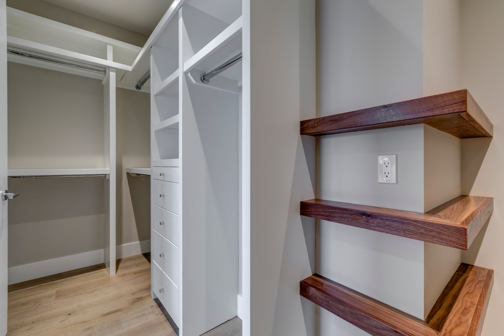 Modelo de armario vestidor unisex tradicional renovado de tamaño medio con armarios abiertos, puertas de armario blancas, suelo de madera clara y suelo beige