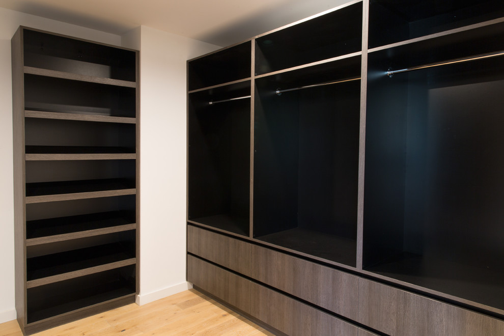Imagen de armario vestidor unisex minimalista grande con armarios con paneles lisos, puertas de armario de madera en tonos medios y suelo de madera clara