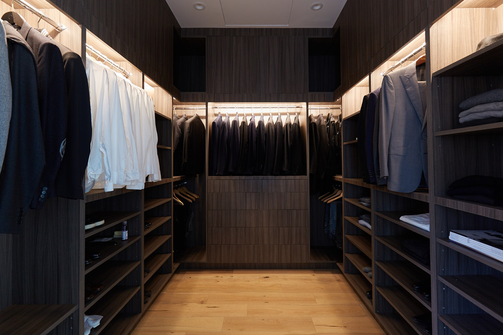 Foto de armario vestidor de hombre minimalista de tamaño medio con armarios con paneles lisos, puertas de armario de madera en tonos medios y suelo de madera clara