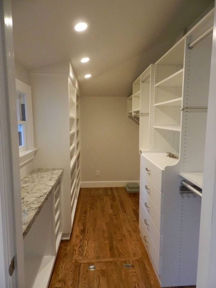 Imagen de armario vestidor unisex actual de tamaño medio con armarios con paneles lisos, puertas de armario blancas y suelo de madera en tonos medios