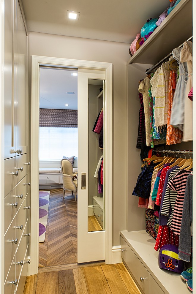 Ejemplo de armario vestidor de mujer actual pequeño con puertas de armario grises y suelo de madera en tonos medios