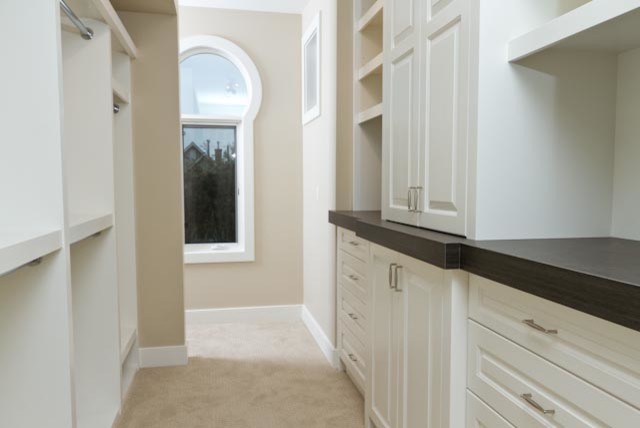 Medium sized traditional gender neutral walk-in wardrobe in Calgary with raised-panel cabinets, white cabinets, carpet and beige floors.