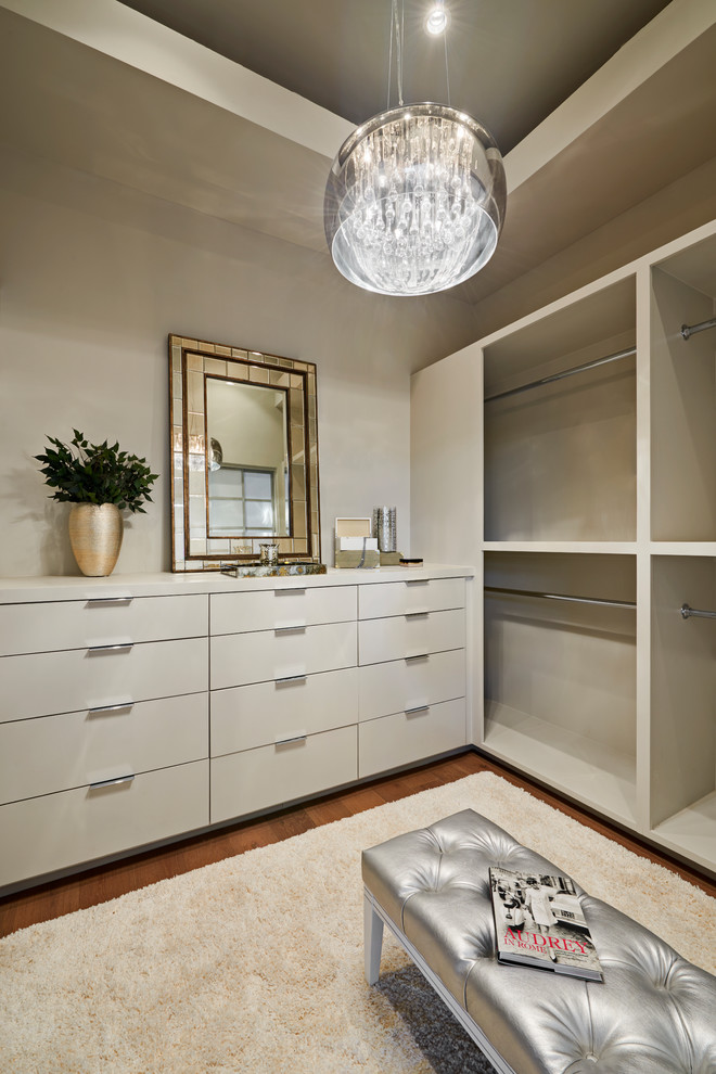 Imagen de armario vestidor actual grande con armarios con paneles lisos, puertas de armario blancas y suelo de madera en tonos medios