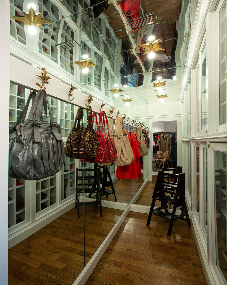 Modelo de armario vestidor de mujer tradicional grande con armarios con rebordes decorativos, puertas de armario blancas, suelo de madera oscura y suelo marrón