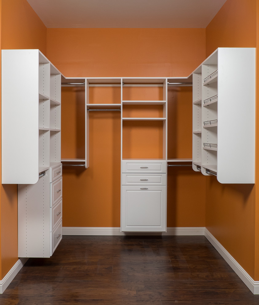 Ejemplo de armario y vestidor unisex clásico con armarios con paneles con relieve, puertas de armario blancas y suelo de madera oscura