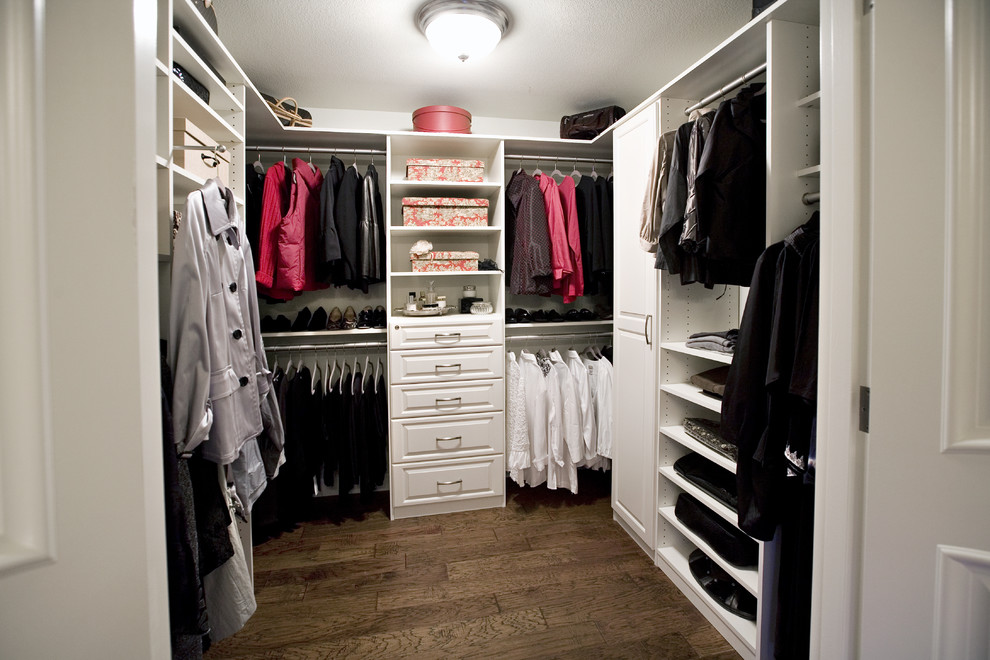 Ejemplo de armario vestidor unisex clásico de tamaño medio con armarios con paneles con relieve, puertas de armario blancas, suelo de madera en tonos medios y suelo marrón