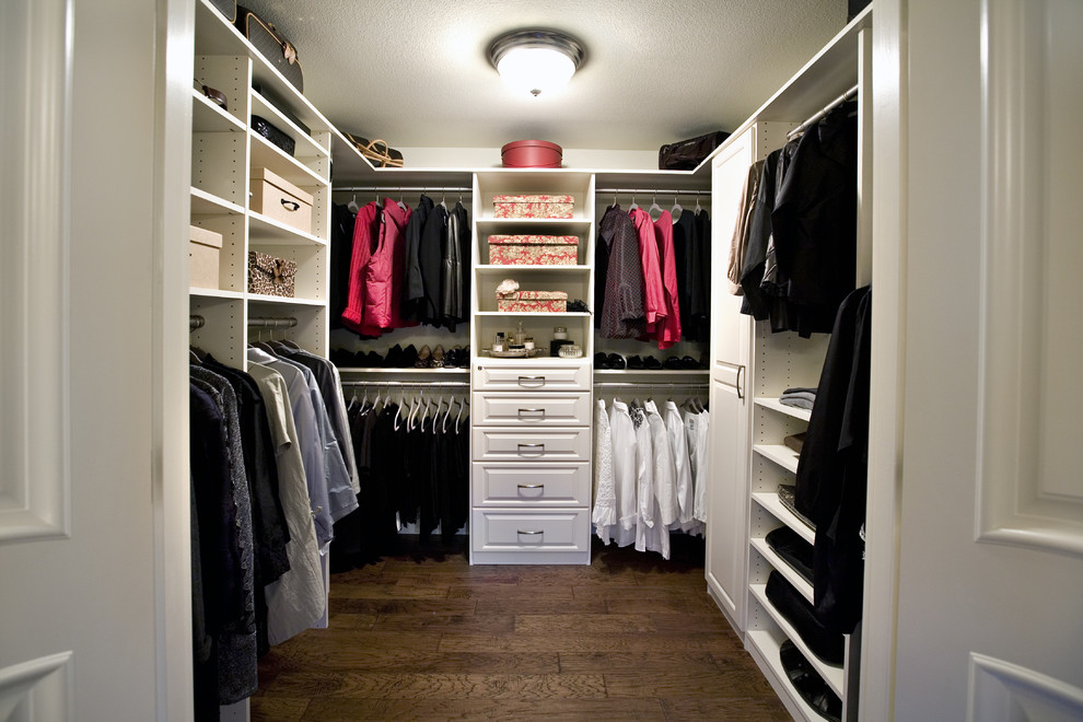 Imagen de armario vestidor unisex tradicional de tamaño medio con armarios con paneles con relieve, puertas de armario blancas, suelo de madera en tonos medios y suelo marrón
