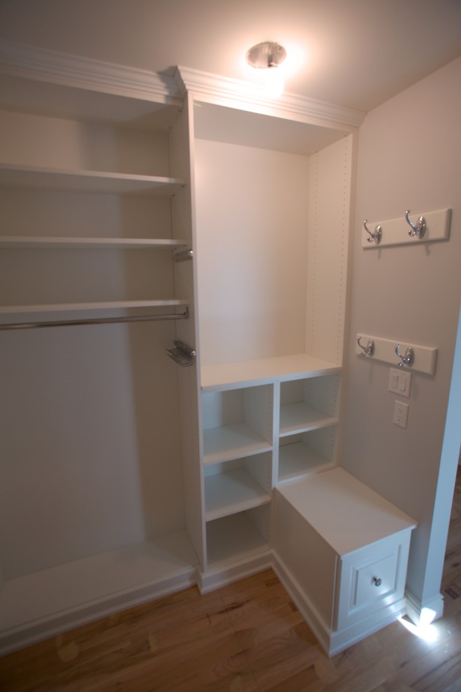 Example of a mid-sized classic gender-neutral light wood floor and brown floor walk-in closet design in Newark with open cabinets and white cabinets