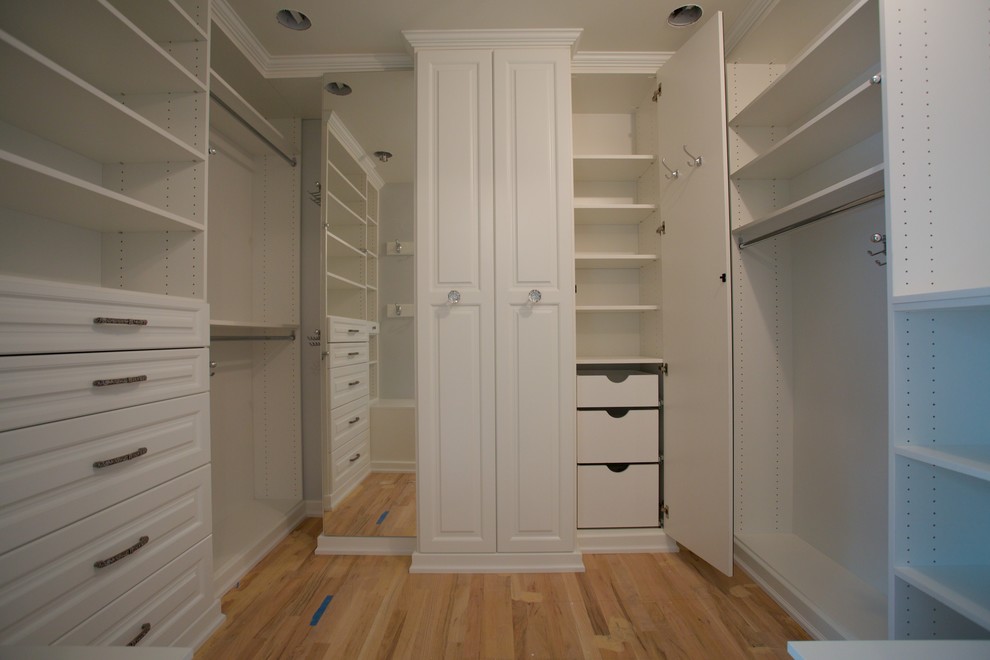 Example of a mid-sized classic gender-neutral light wood floor and brown floor walk-in closet design in New York with open cabinets and white cabinets