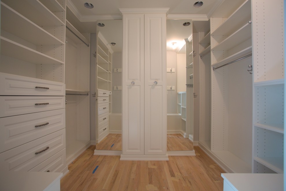 Foto de armario vestidor unisex tradicional de tamaño medio con armarios abiertos, puertas de armario blancas, suelo de madera clara y suelo marrón
