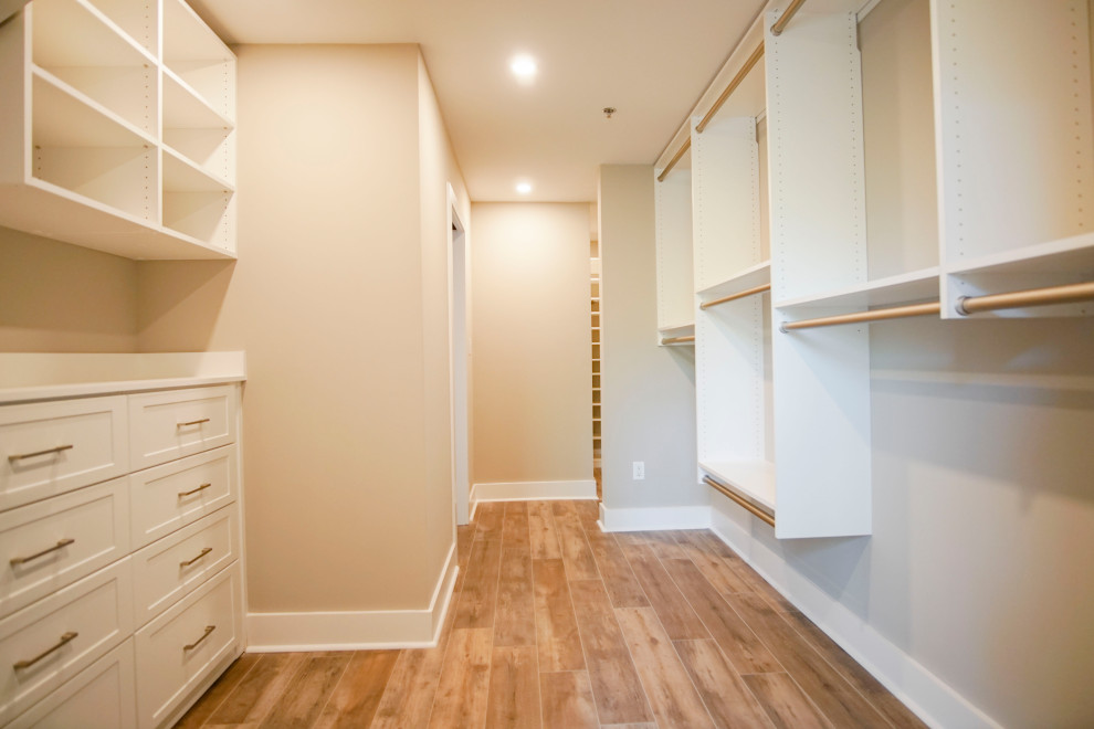 Example of a mid-sized urban gender-neutral vinyl floor, brown floor and wood ceiling walk-in closet design in Atlanta with recessed-panel cabinets and white cabinets
