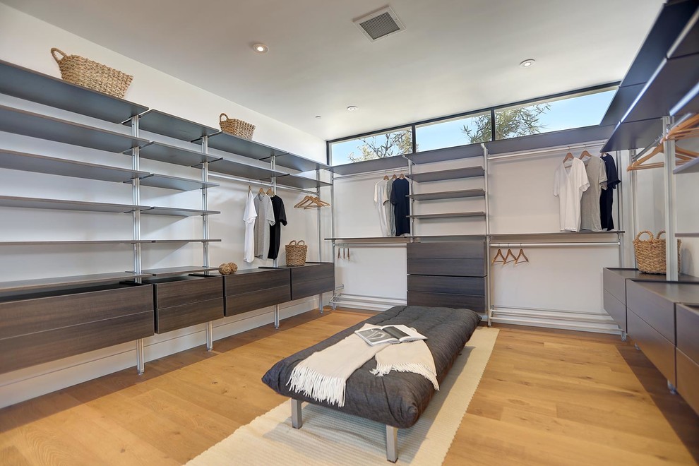 Inspiration for a large modern gender-neutral medium tone wood floor walk-in closet remodel in Los Angeles with flat-panel cabinets and dark wood cabinets