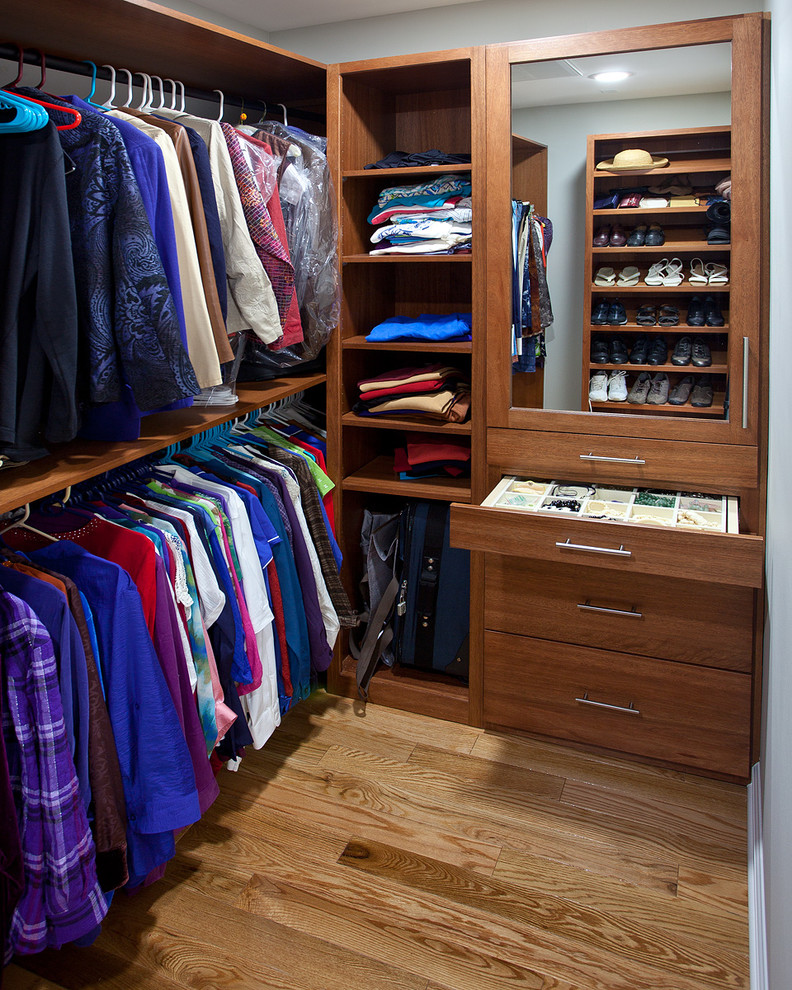 Modelo de armario vestidor unisex tradicional renovado de tamaño medio con armarios con paneles lisos, puertas de armario de madera oscura y suelo de madera clara