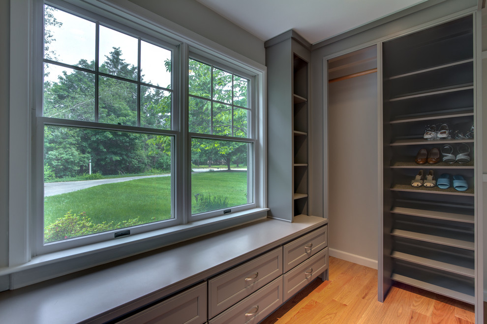 Walk-in closet - mid-sized contemporary gender-neutral medium tone wood floor walk-in closet idea in Boston with recessed-panel cabinets and gray cabinets
