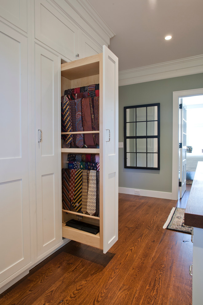 Ejemplo de vestidor unisex clásico grande con armarios con rebordes decorativos, puertas de armario blancas y suelo de madera en tonos medios