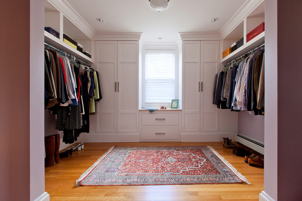 Imagen de armario vestidor unisex clásico grande con armarios estilo shaker, puertas de armario blancas, suelo de madera clara y suelo beige