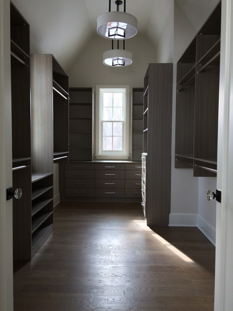 Design ideas for a medium sized farmhouse gender neutral walk-in wardrobe in Chicago with flat-panel cabinets, grey cabinets and medium hardwood flooring.