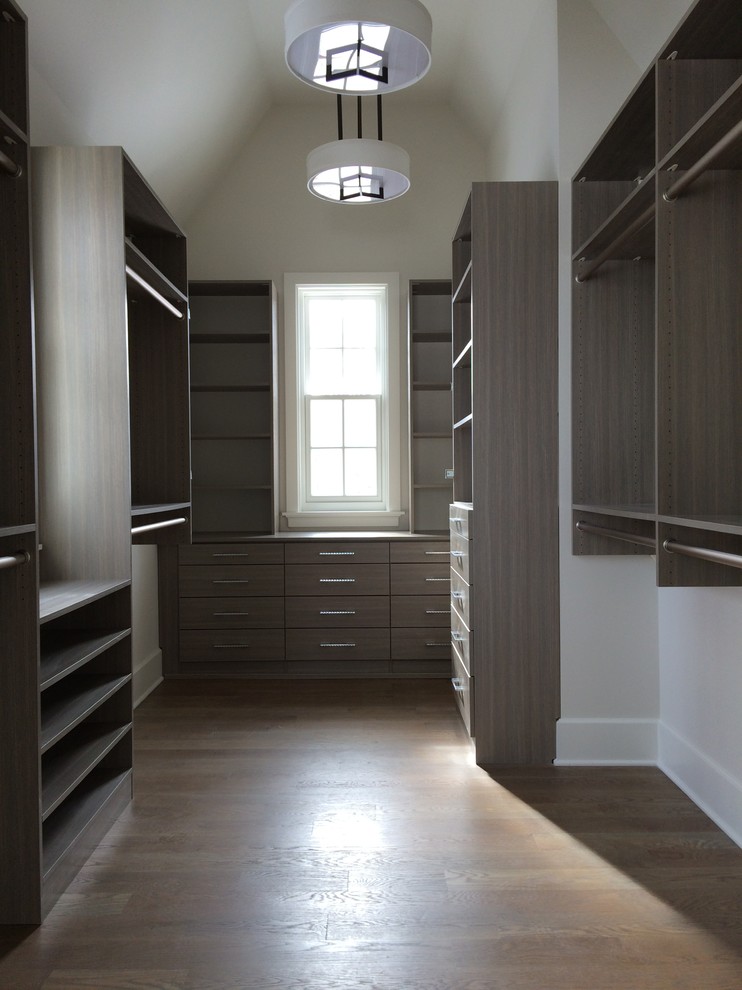 Ejemplo de armario vestidor unisex de estilo de casa de campo de tamaño medio con armarios con paneles lisos, puertas de armario grises y suelo de madera en tonos medios