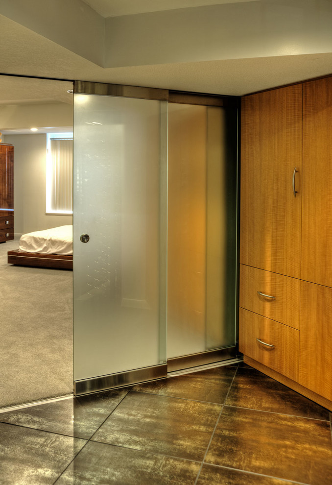 Immagine di una grande cabina armadio unisex contemporanea con ante lisce, ante in legno chiaro, pavimento con piastrelle in ceramica e pavimento nero