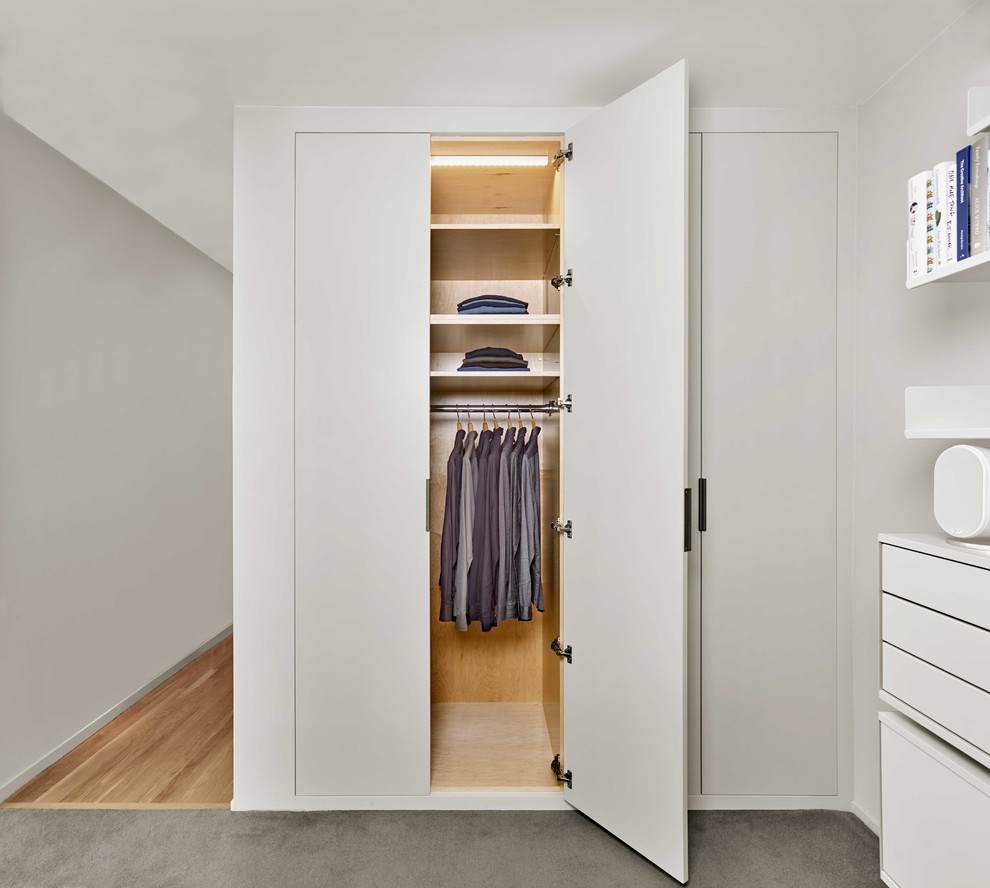 Стильный дизайн: шкаф в нише среднего размера, унисекс в стиле модернизм с плоскими фасадами, белыми фасадами, полом из фанеры и серым полом - последний тренд