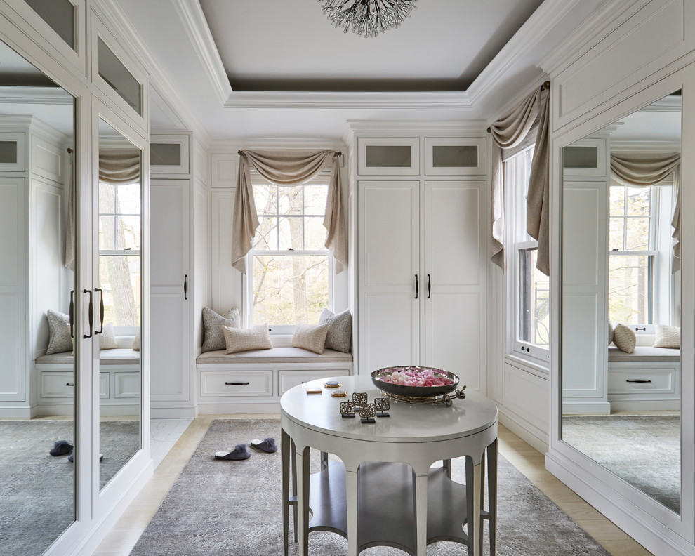 Inspiration for a traditional dressing room for women in Chicago with recessed-panel cabinets, white cabinets and light hardwood flooring.
