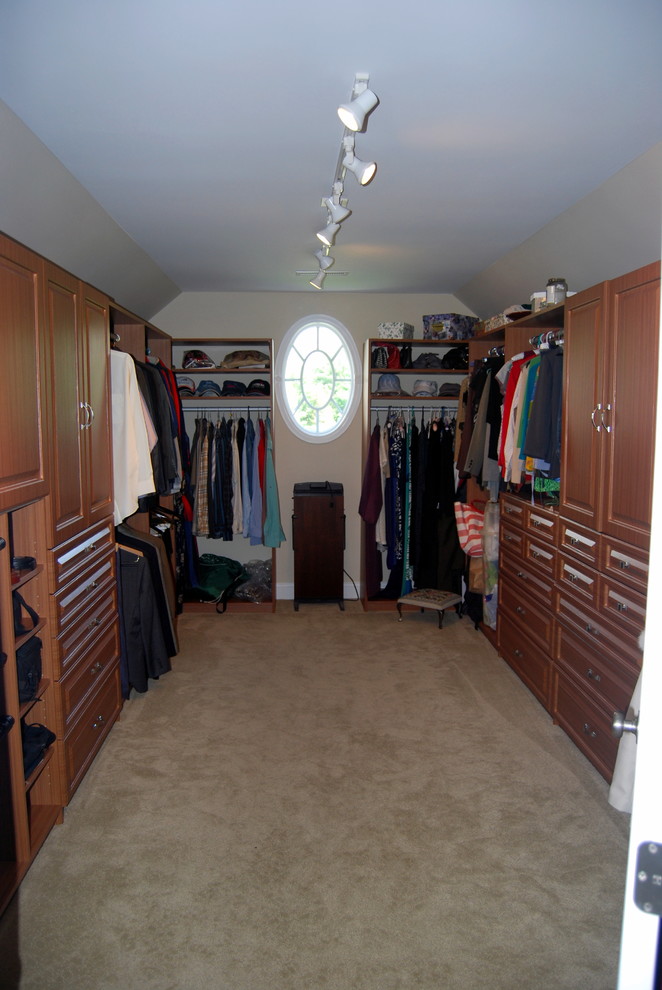 Ejemplo de armario vestidor unisex clásico grande con armarios con paneles con relieve, puertas de armario de madera en tonos medios y moqueta