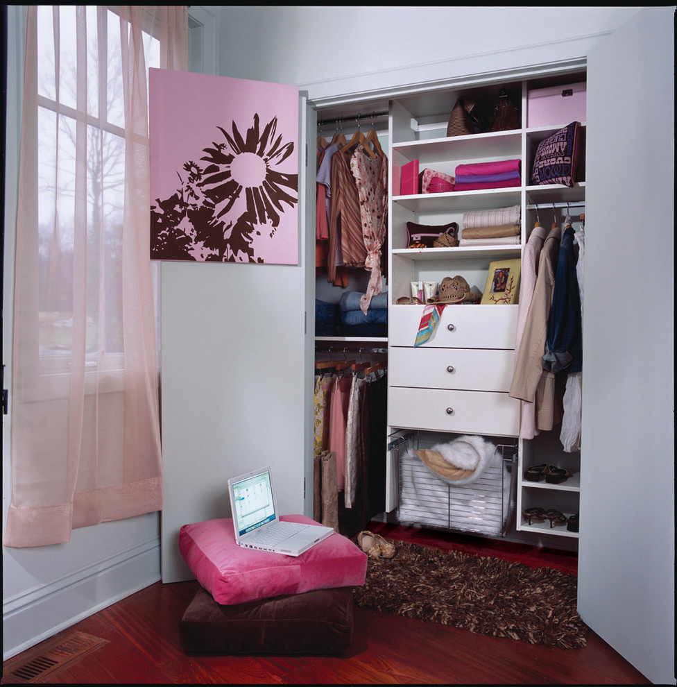 Imagen de armario de mujer actual de tamaño medio con suelo de madera en tonos medios y puertas de armario blancas