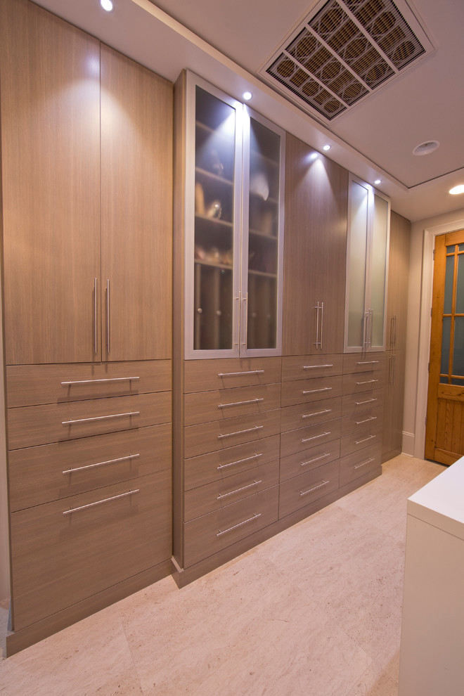 Inspiration for an expansive modern dressing room for women in New Orleans with flat-panel cabinets, travertine flooring and beige cabinets.