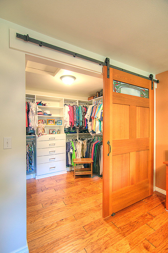Ejemplo de armario vestidor unisex clásico de tamaño medio con armarios con paneles lisos, puertas de armario blancas y suelo de madera en tonos medios
