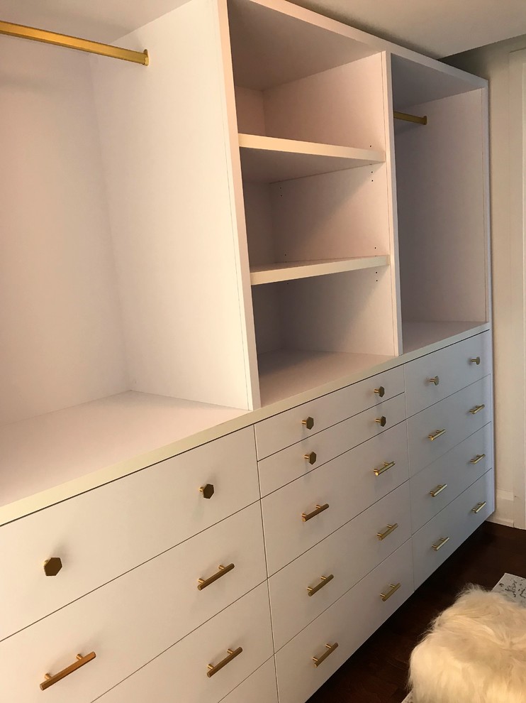 Diseño de armario vestidor unisex contemporáneo pequeño con armarios con paneles lisos, puertas de armario blancas y suelo de madera oscura