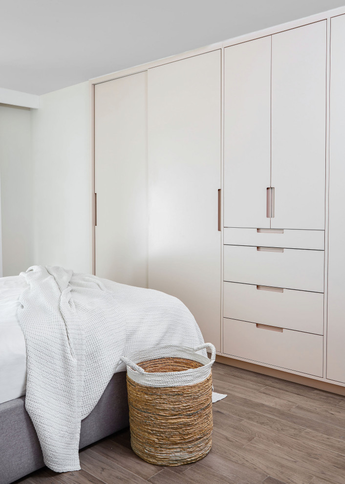 Cette photo montre une armoire encastrée tendance de taille moyenne et neutre avec un placard à porte plane, un sol en bois brun et un sol gris.