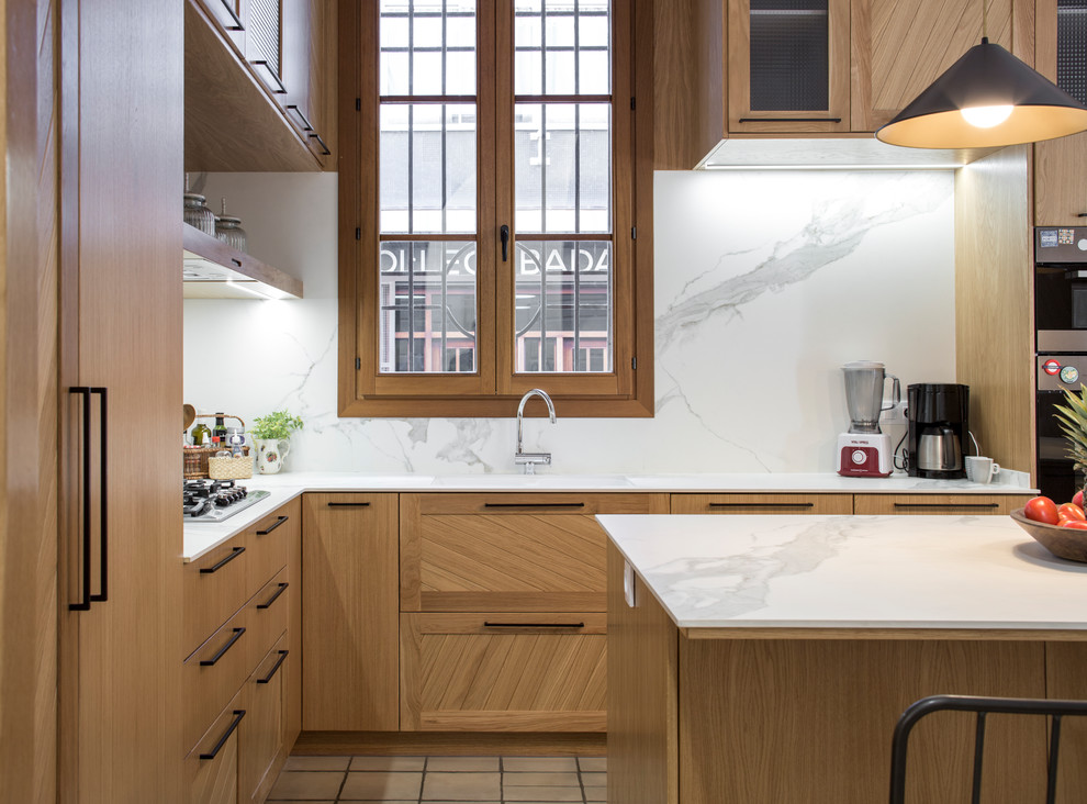 Example of a large transitional u-shaped ceramic tile and multicolored floor eat-in kitchen design in Barcelona with an undermount sink, raised-panel cabinets, medium tone wood cabinets, marble countertops, white backsplash, marble backsplash, stainless steel appliances and an island
