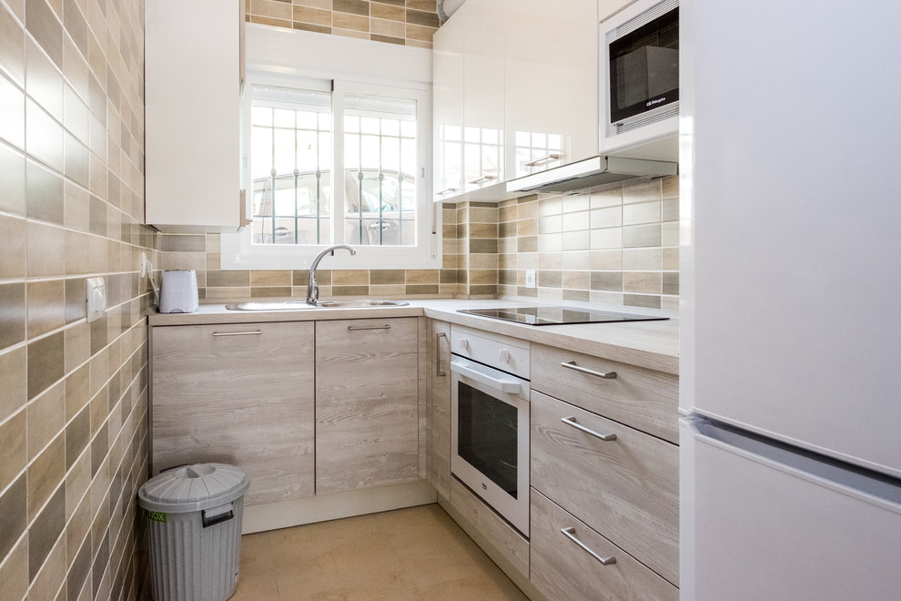This is an example of a small classic l-shaped enclosed kitchen in Malaga with a double-bowl sink, flat-panel cabinets, light wood cabinets, wood worktops, multi-coloured splashback, white appliances and no island.