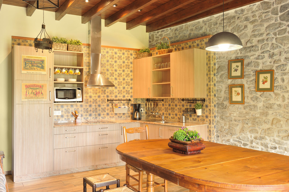 Landhaus Wohnküche in L-Form mit flächenbündigen Schrankfronten, hellen Holzschränken, bunter Rückwand, weißen Elektrogeräten, braunem Holzboden und braunem Boden in Sonstige