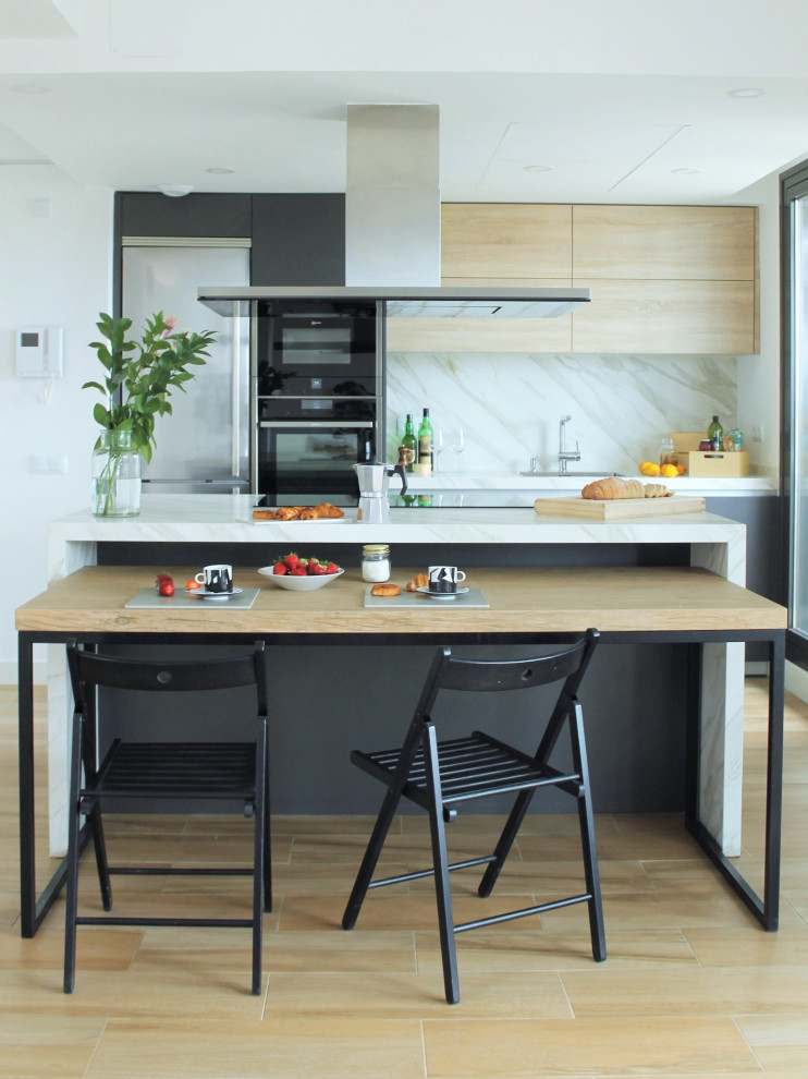 Idée de décoration pour une cuisine américaine parallèle design en bois clair avec un évier encastré, un placard à porte plane, une crédence blanche, un électroménager en acier inoxydable, parquet clair, îlot, un sol beige et un plan de travail turquoise.