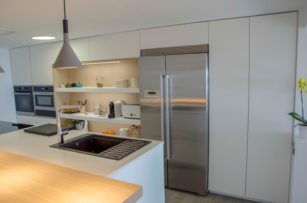 This is an example of an expansive scandinavian single-wall kitchen/diner in Malaga with a belfast sink, open cabinets, white cabinets, engineered stone countertops, stainless steel appliances, porcelain flooring, an island, white worktops and grey floors.