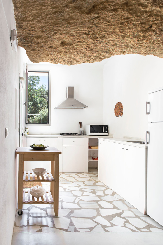 Esempio di una cucina a L mediterranea chiusa e di medie dimensioni con ante lisce, ante bianche, paraspruzzi bianco, nessuna isola e elettrodomestici bianchi