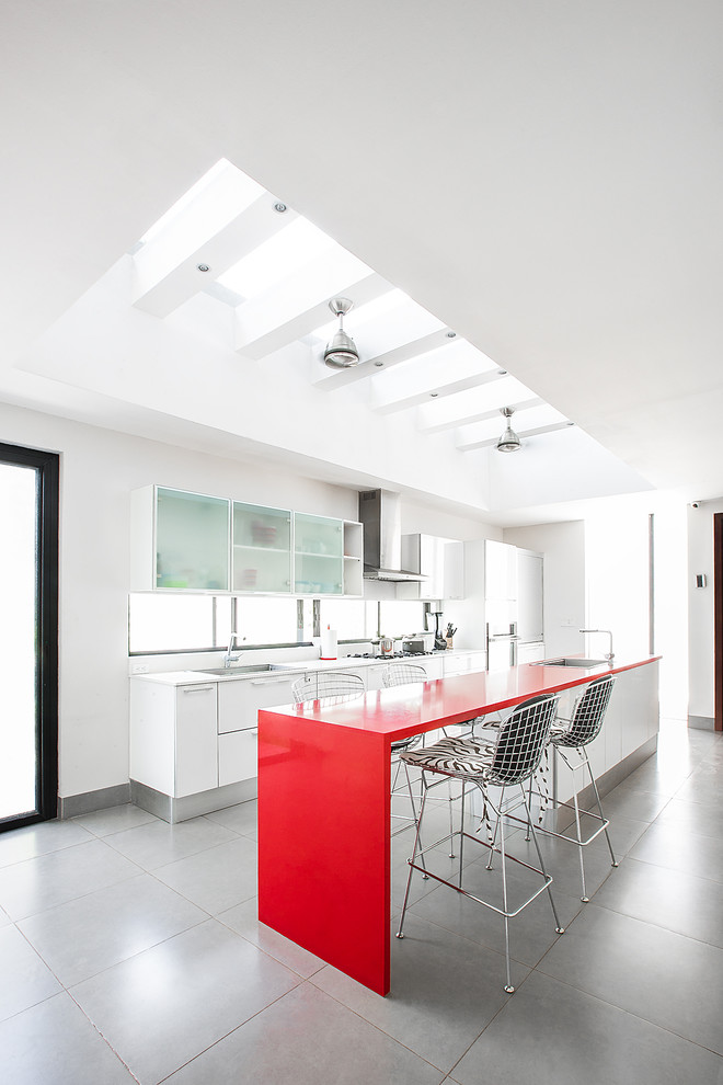 Zweizeilige Moderne Wohnküche mit Unterbauwaschbecken, flächenbündigen Schrankfronten, weißen Schränken, Küchenrückwand in Weiß, Rückwand-Fenster, Kücheninsel, grauem Boden und roter Arbeitsplatte in Sonstige