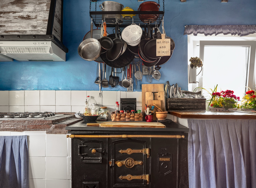 На фото: кухня среднего размера в стиле рустика с деревянной столешницей, белым фартуком, фартуком из керамической плитки, коричневой столешницей и черной техникой