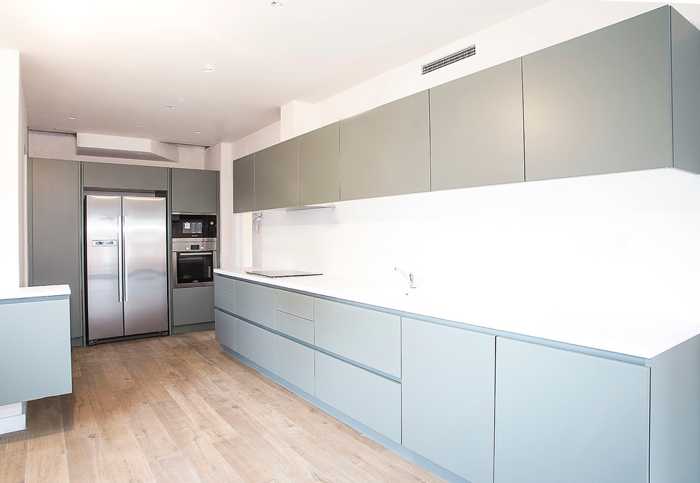 Idéer för att renovera ett mellanstort funkis kök, med en enkel diskho, grå skåp, vitt stänkskydd, rostfria vitvaror och mellanmörkt trägolv