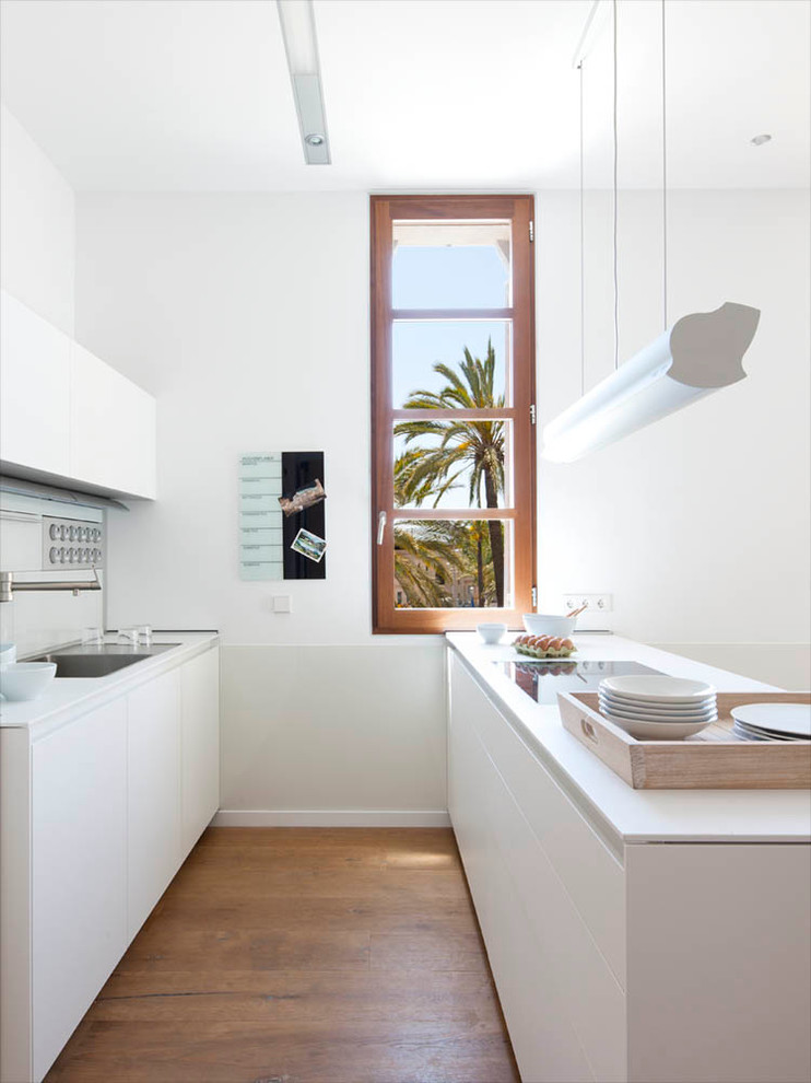 Photo of a medium sized contemporary galley open plan kitchen in Other with flat-panel cabinets, white cabinets, white splashback, medium hardwood flooring and a breakfast bar.