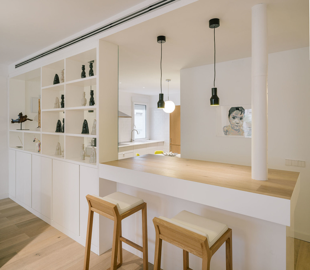 Aménagement d'une grande cuisine scandinave avec des portes de placard blanches, un plan de travail en bois et une crédence blanche.