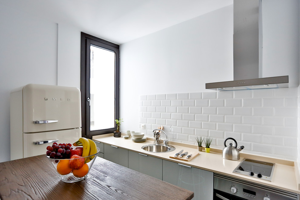 Идея дизайна: маленькая прямая кухня-гостиная в скандинавском стиле с плоскими фасадами, белым фартуком, фартуком из плитки кабанчик, цветной техникой и островом для на участке и в саду
