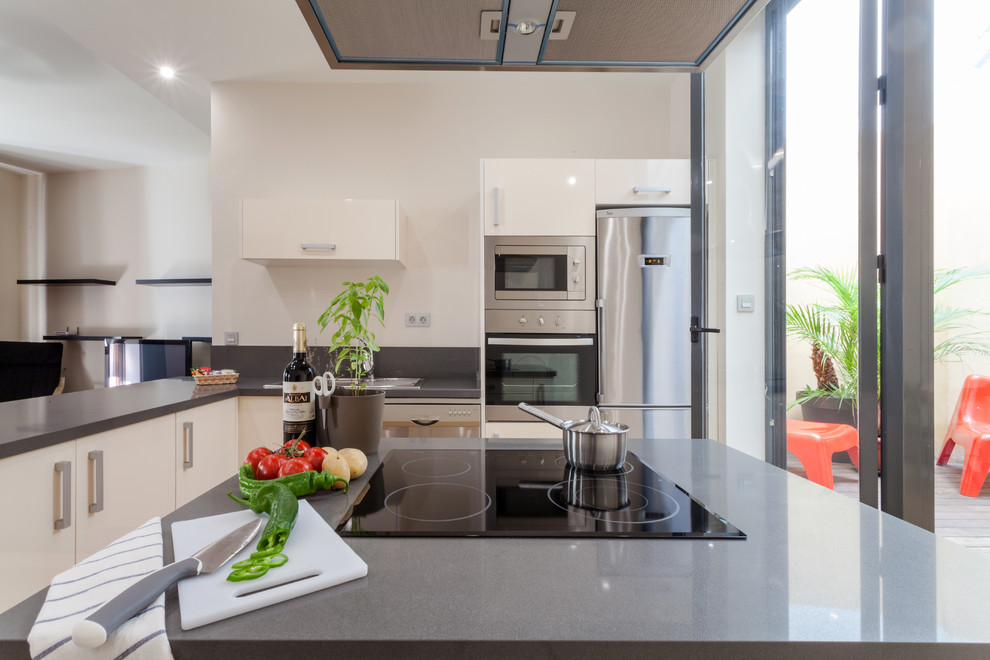 This is an example of a medium sized contemporary l-shaped open plan kitchen in Seville with stainless steel appliances and an island.