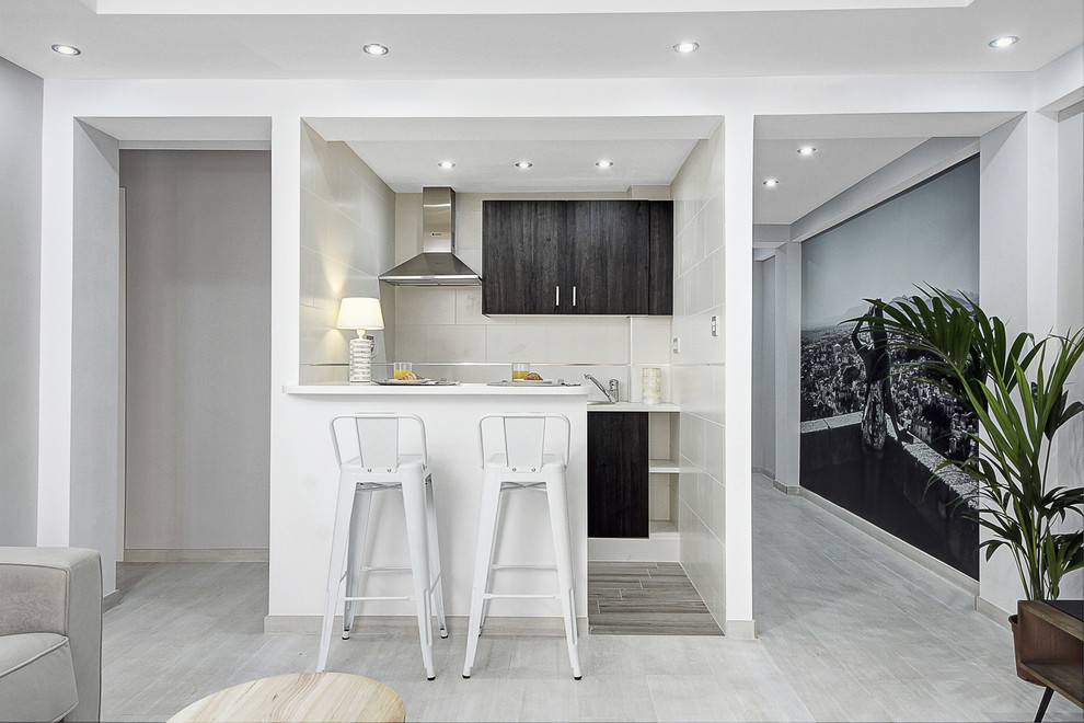 Small classic galley open plan kitchen in Other with a breakfast bar, white floors, flat-panel cabinets, black cabinets, white worktops, grey splashback and stainless steel appliances.