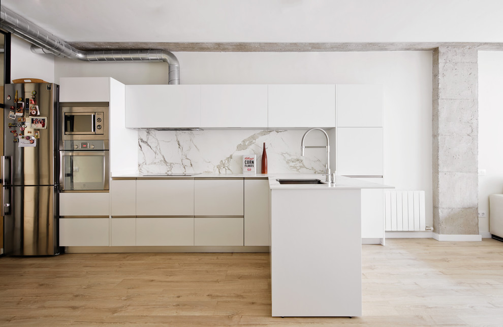 Offene, Mittelgroße Moderne Küche in L-Form mit Waschbecken, flächenbündigen Schrankfronten, weißen Schränken, Küchenrückwand in Weiß, hellem Holzboden und Halbinsel in Barcelona
