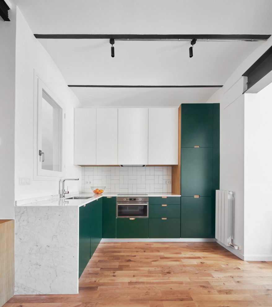 バルセロナにあるコンテンポラリースタイルのおしゃれなL型キッチン (アンダーカウンターシンク、フラットパネル扉のキャビネット、緑のキャビネット、白いキッチンパネル、シルバーの調理設備、無垢フローリング、アイランドなし、茶色い床、白いキッチンカウンター) の写真