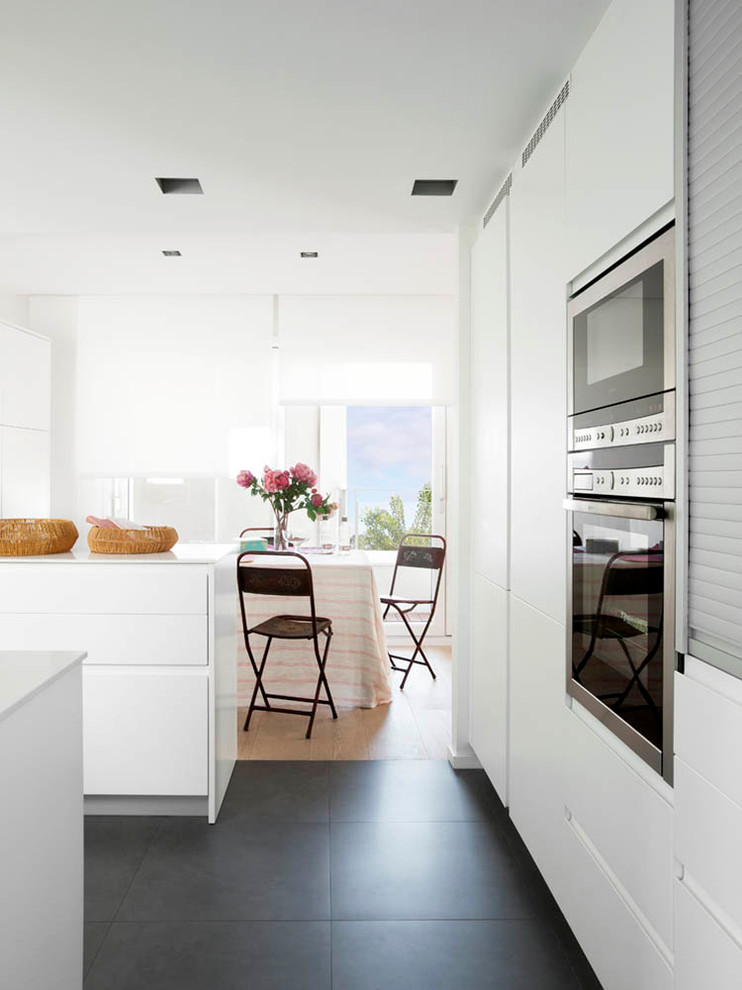 Inredning av ett minimalistiskt stort kök, med släta luckor, vita skåp, bänkskiva i kvarts, integrerade vitvaror, klinkergolv i porslin och en köksö