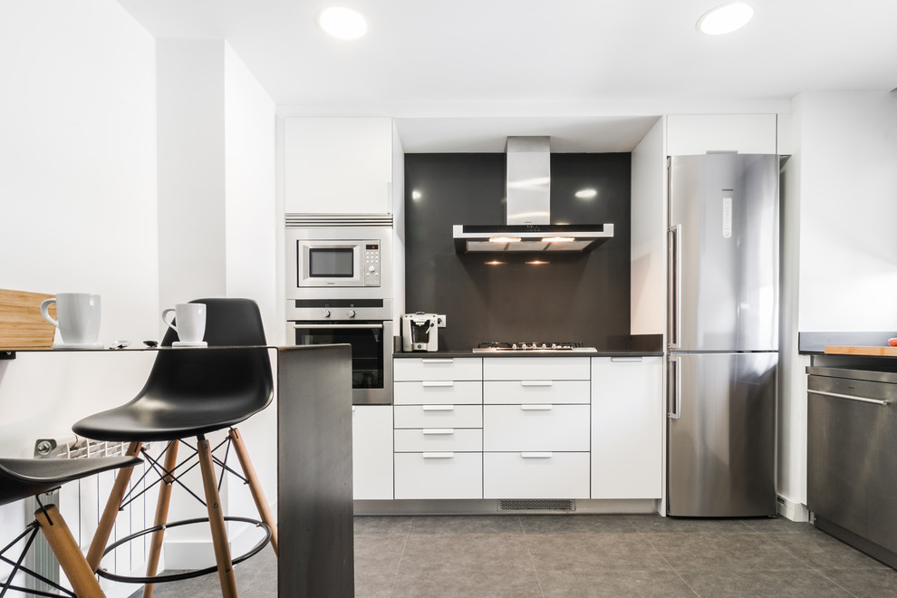 Esempio di una piccola cucina minimalista con ante lisce, ante bianche, paraspruzzi nero, penisola e pavimento nero