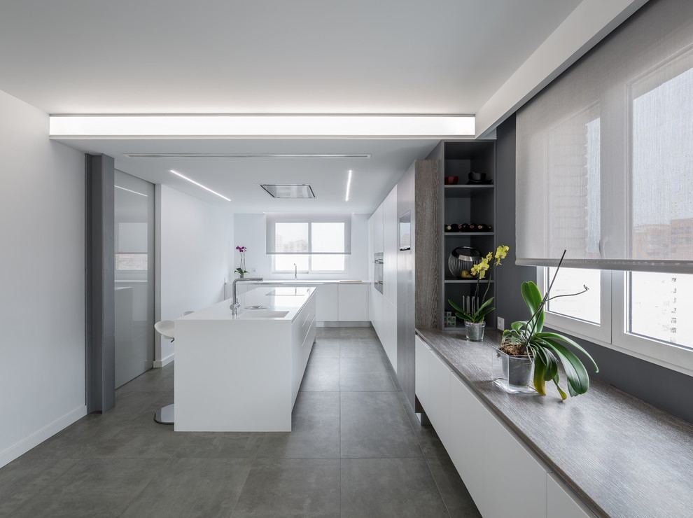Immagine di una grande cucina minimalista chiusa con ante lisce, ante bianche, top in superficie solida e paraspruzzi bianco